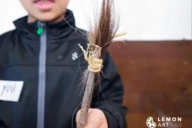 Niño muestra un pincel prehistórico