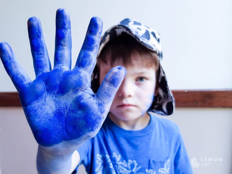 Niño con pigmento azul klein en su mano